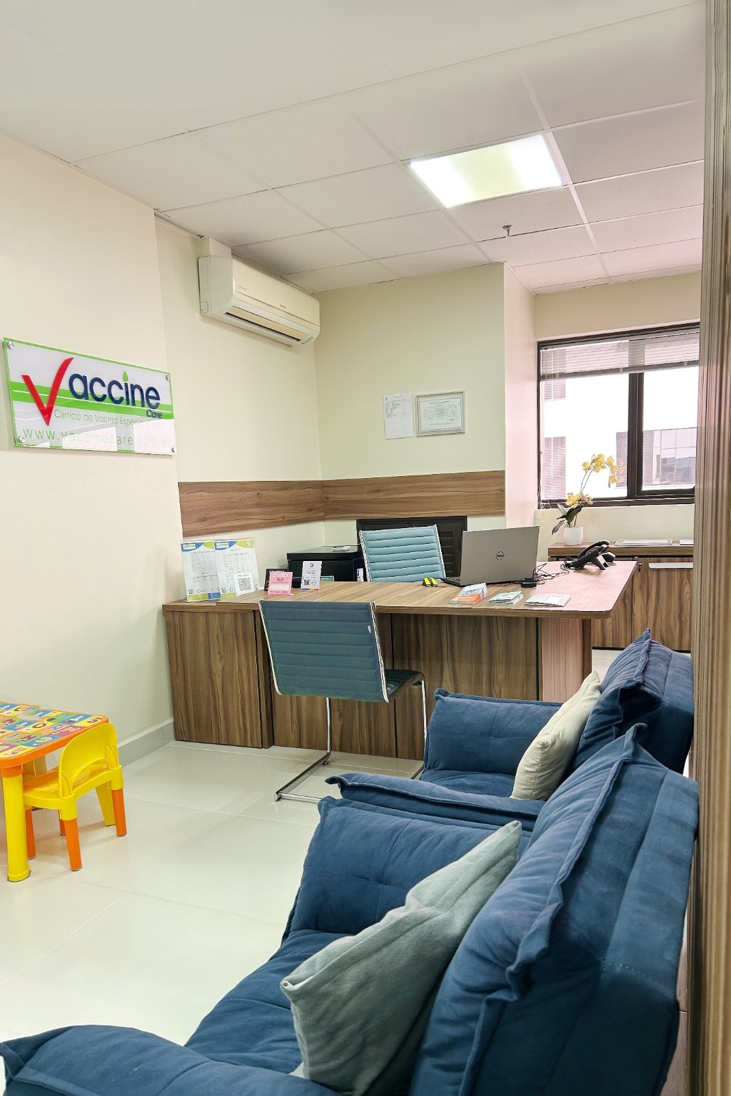 Recepção da Vaccine Care Arujá, com a placa da clínica e um cantinho infantil